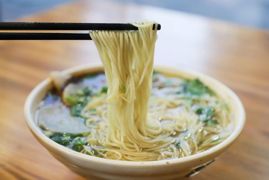 Savor the mouthwatering taste of fresh ramen noodles lifted by chopsticks.