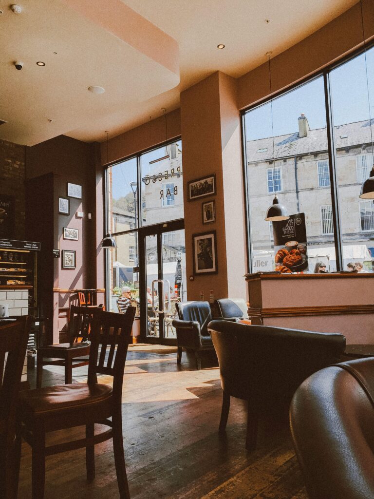 Warm and inviting café interior with wooden flooring and large windows letting in natural daylight.